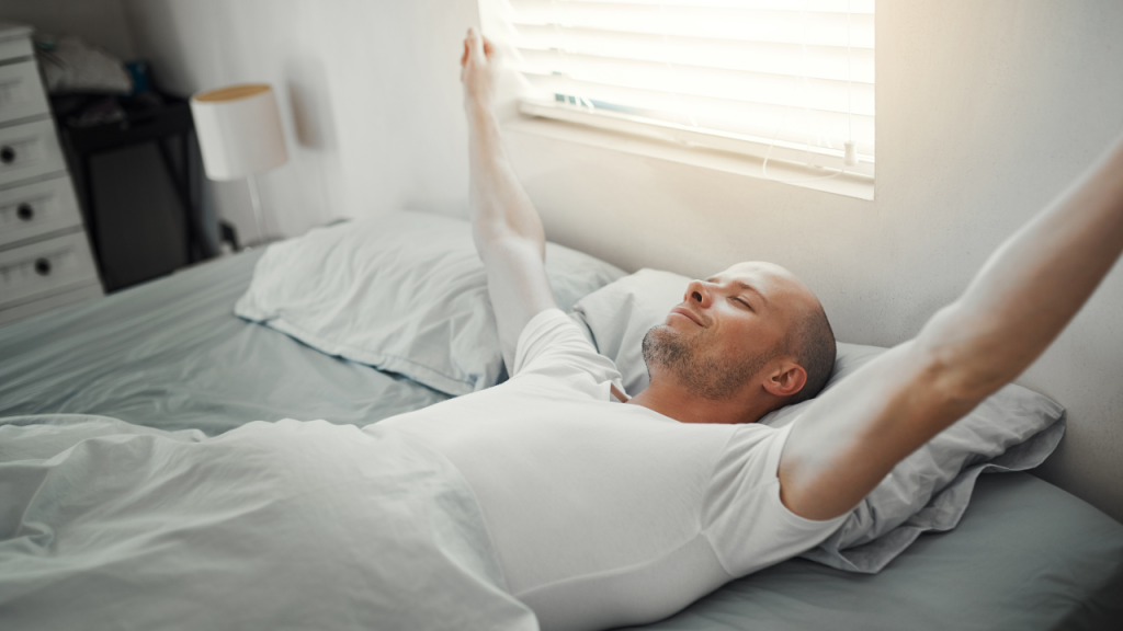 ベッドで眠っていた男性がすっきりとした目覚めを迎えている画像